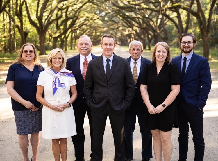 A team picture of the Clements McGovern Financial Consulting Group on a dirt road with green overhanging trees in the background